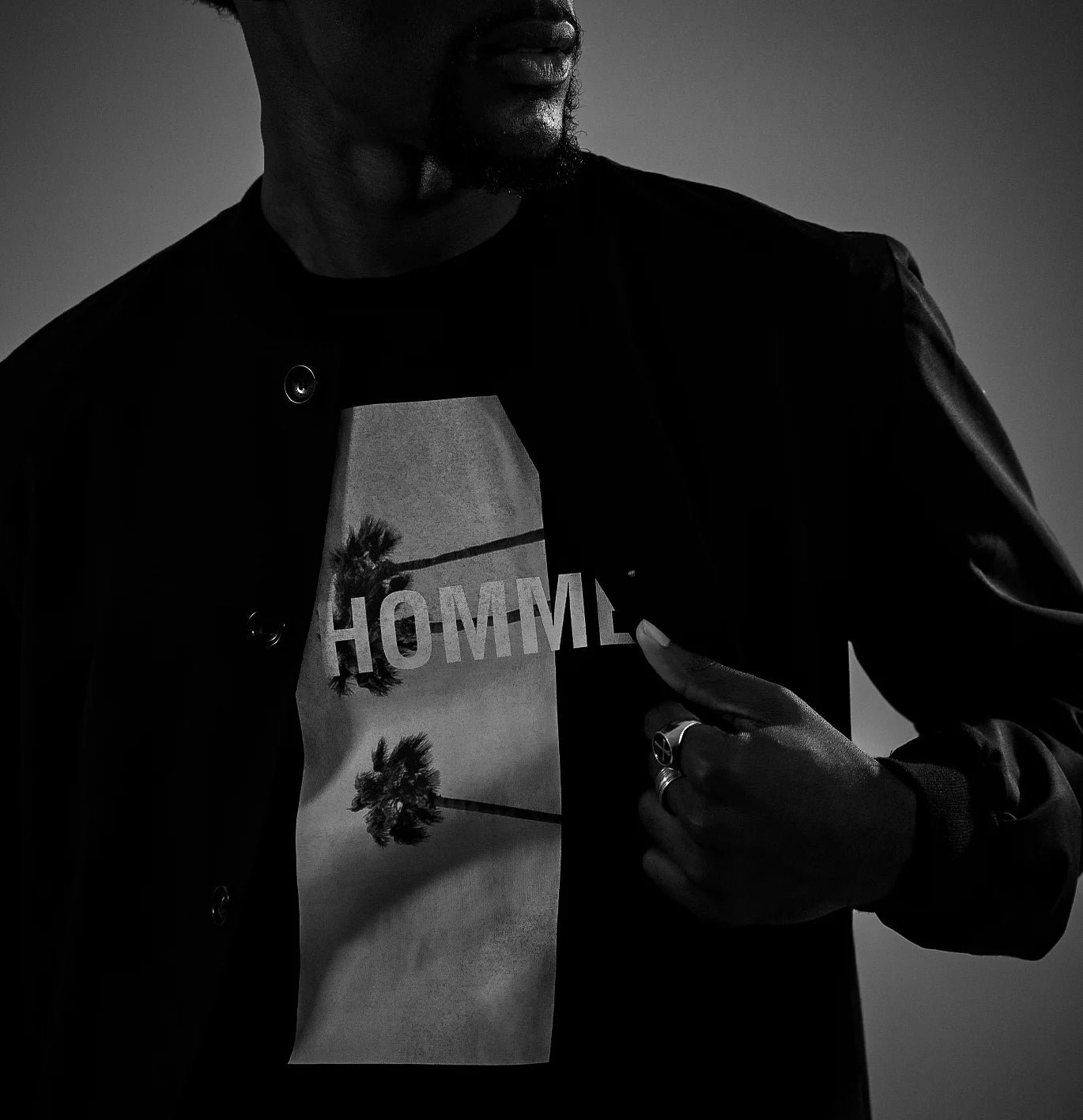 Model wearing a Les Hommes black jacket with a graphic design 
