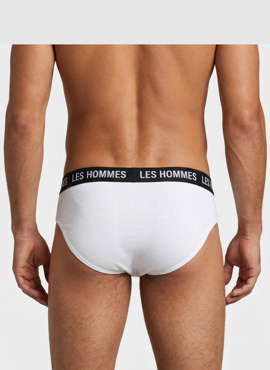 back view of a male model wearing white briefs with a black waistband reading Les Hommes
