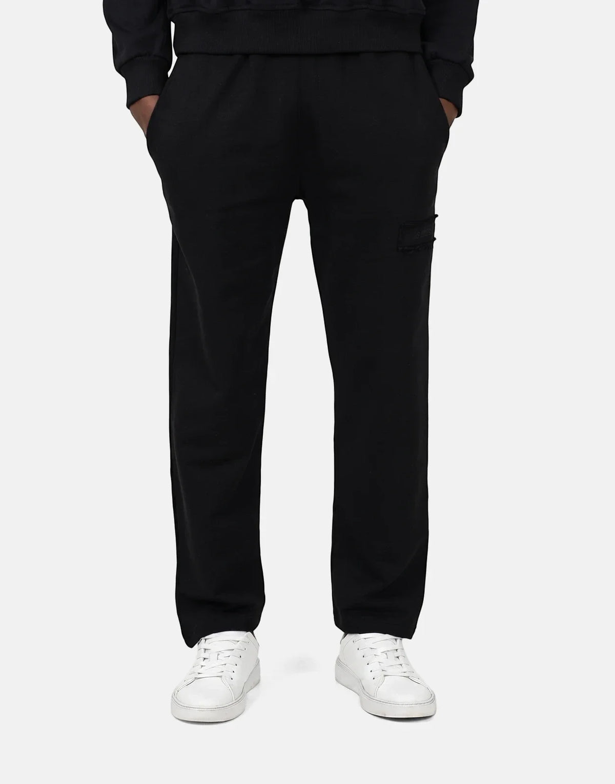 Les Hommes Black Jogger worn by a person, featuring a comfortable fit and white sneakers. Front view.