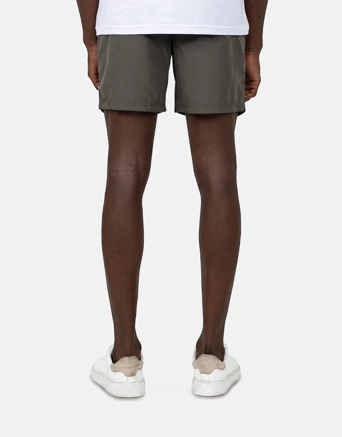 Les Hommes Colour Green Swim Shorts on a male model, seen from the back, paired with white sneakers.