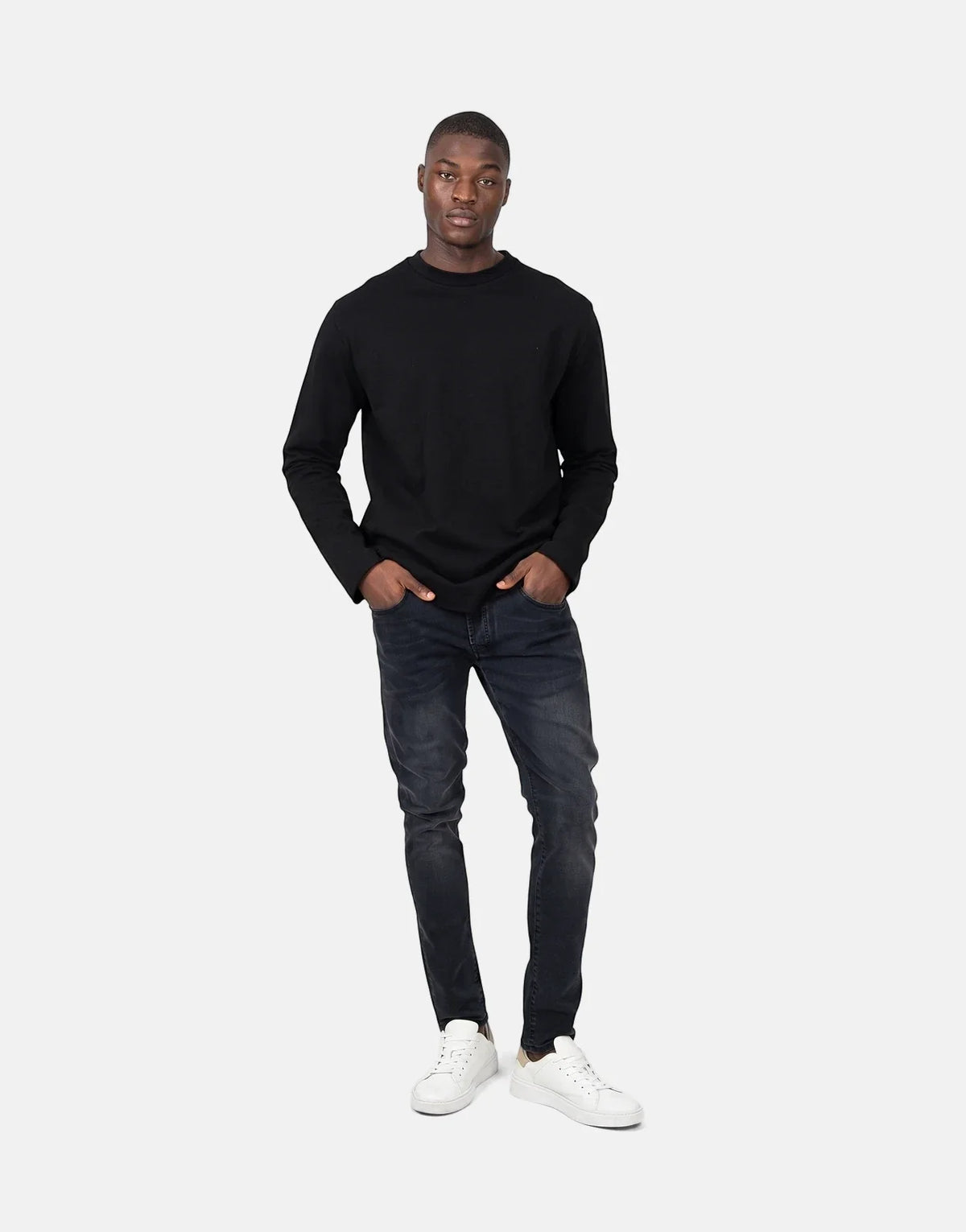 A black long-sleeved Les Hommes Dragonfly sweatshirt on a male model paired with dark jeans and white sneakers.