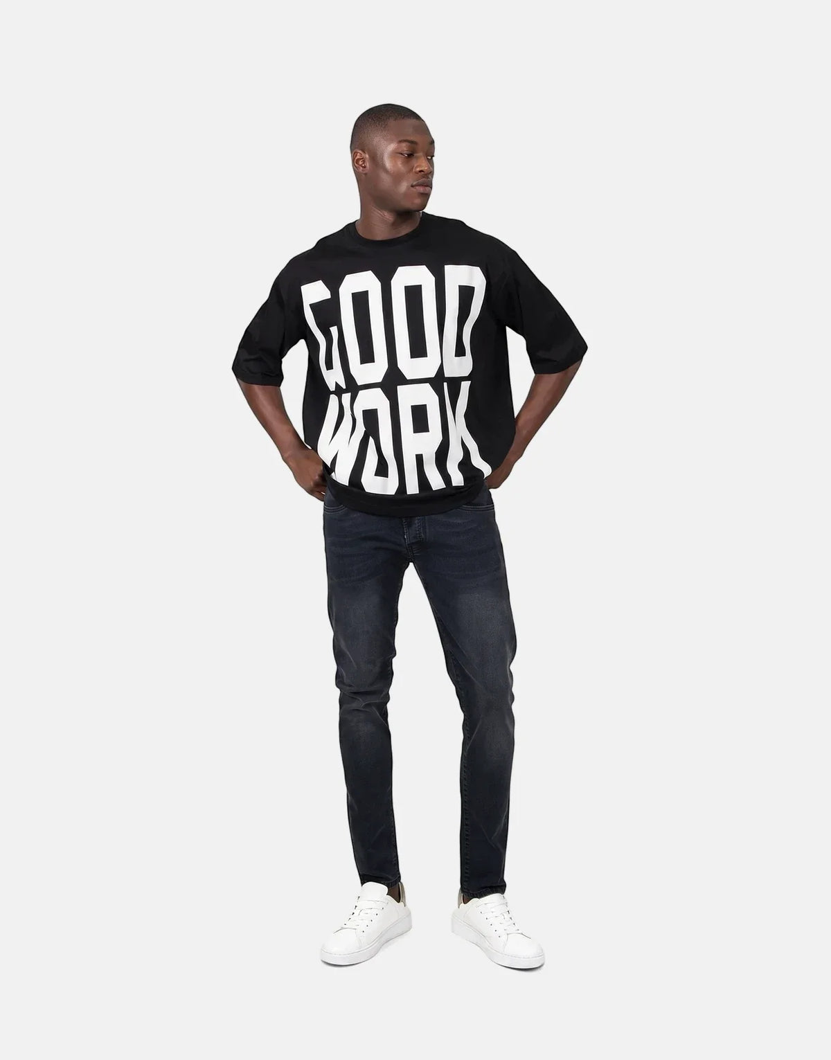 Les Hommes Good Work Black T-Shirt on a male model wearing dark wash jeans and white sneakers.