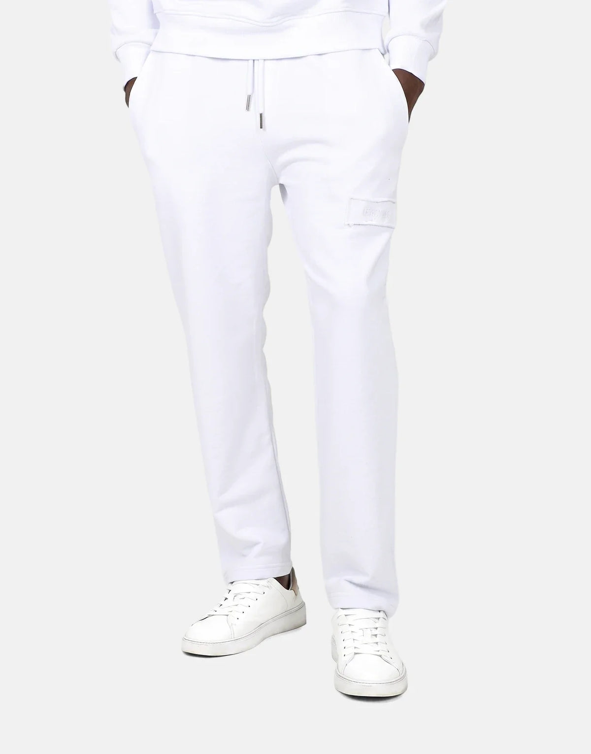 Men's Les Hommes white jogger sweatpants, featuring a drawstring waist, side pockets, and a subtle patch logo on the thigh,