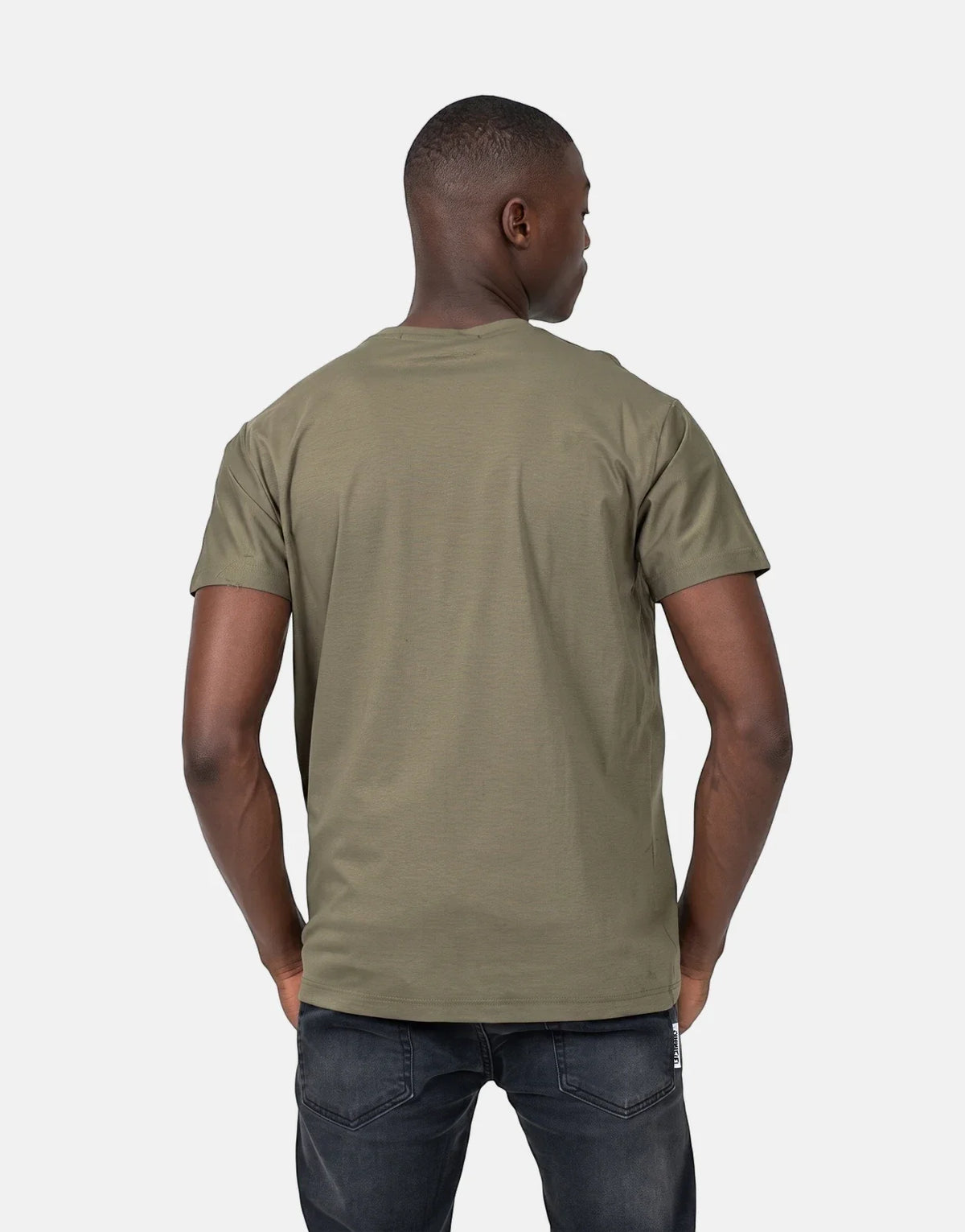 Back view of a male model wearing an olive green Les Hommes t-shirt and dark jeans.