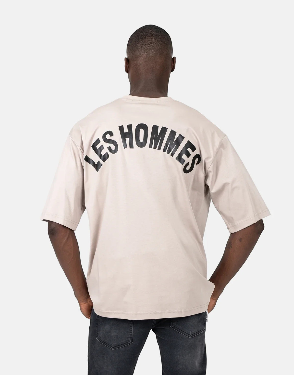 Men's Les Hommes oversized brown t-shirt featuring a distinctive black 'LES HOMMES' logo arched across the back.