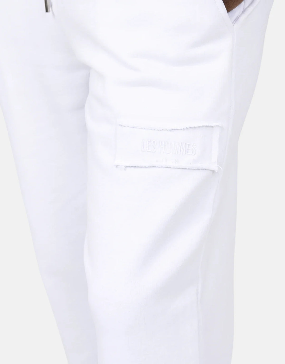 Close-up of Les Hommes White Jogger with a subtle tone-on-tone logo patch on the thigh, showcasing the soft fabric.