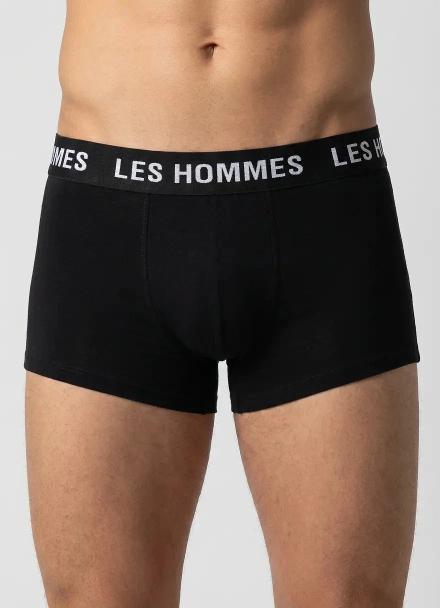 man wears black boxer trunks with a wide elastic waistband that reads Les Hommes